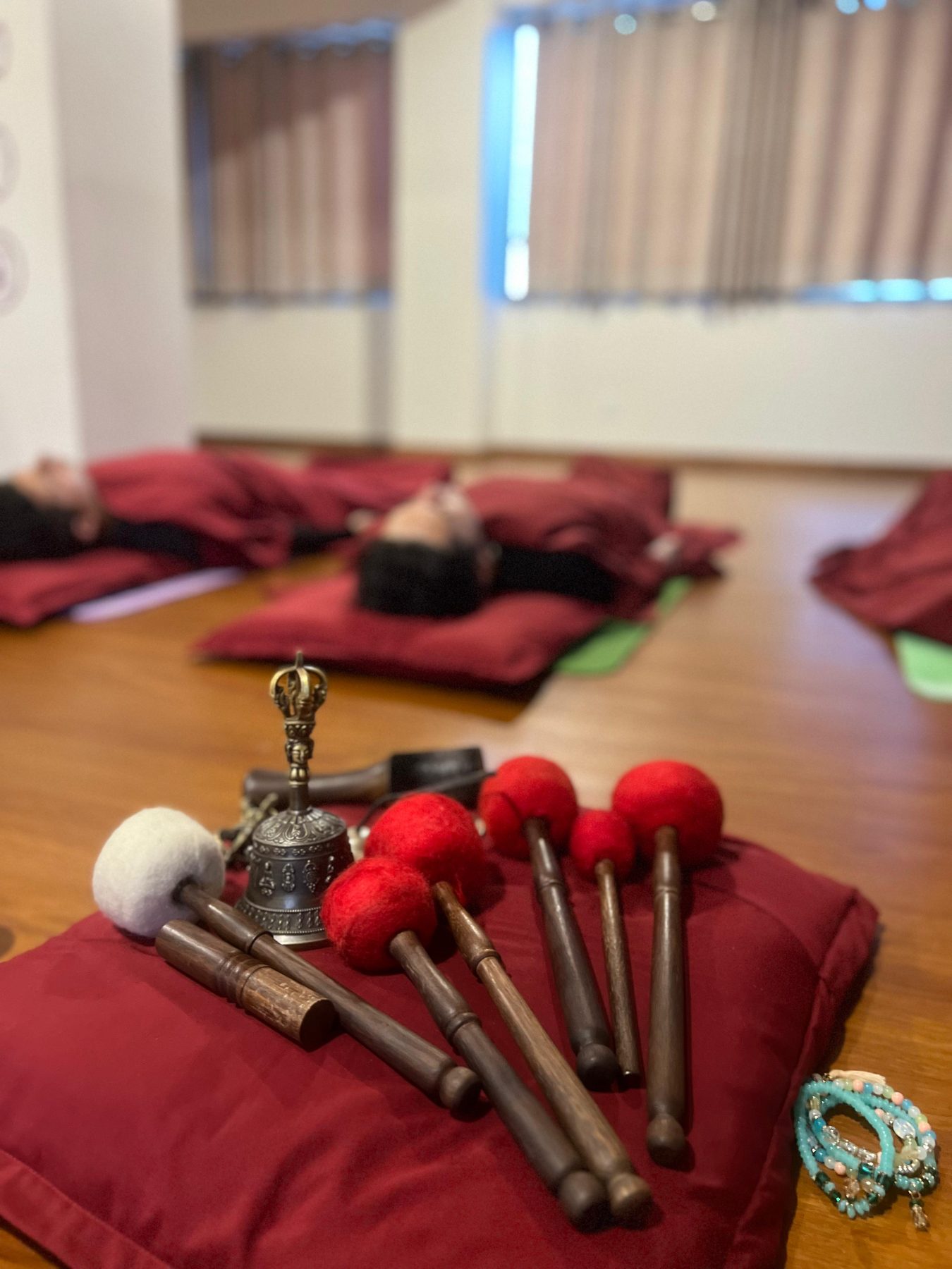 Singing bowl mallets and a Tibetan bell resting on a bolster before a sound healing session in Kathmandu