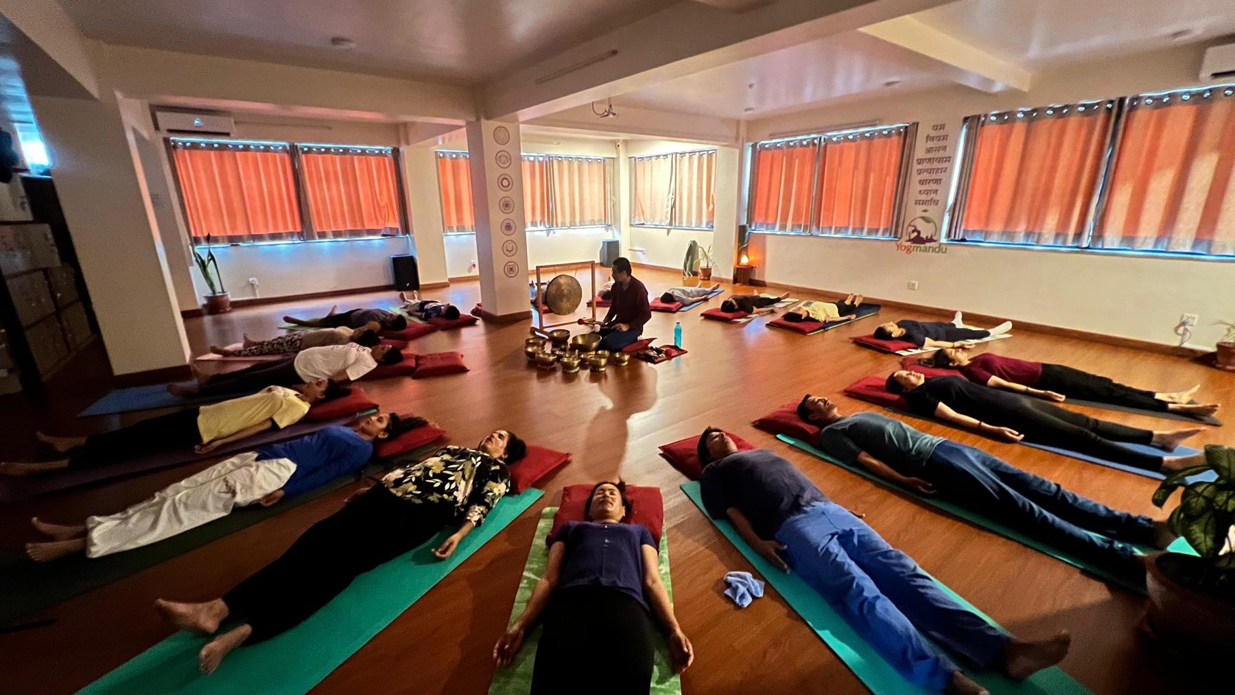 Wide view of a sound healing session at the Yogmandu studio in Kathmandu, students lying on mats with bolsters