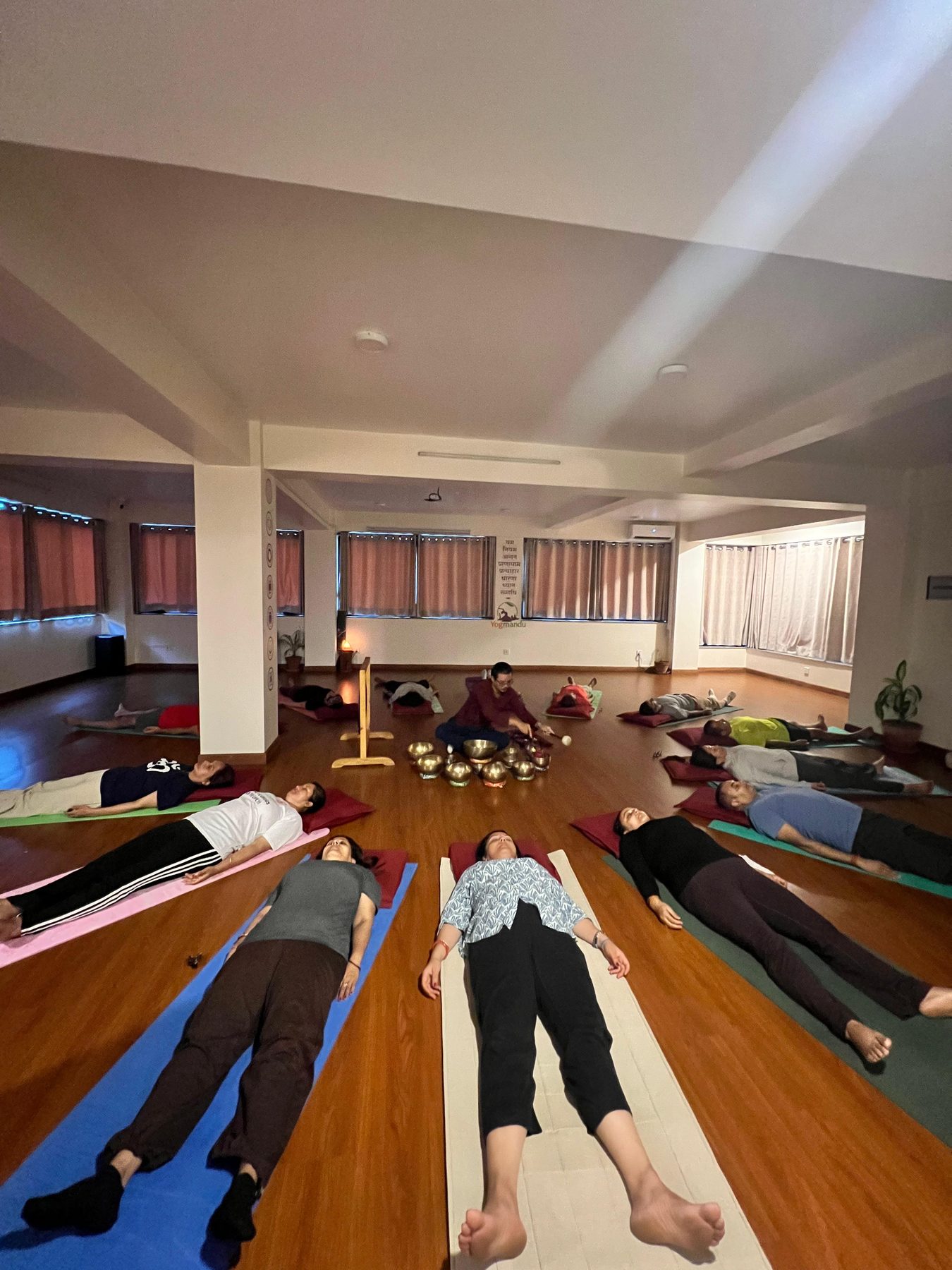 Students in savasana on bolsters around a set of brass singing bowls during a sound meditation in Kathmandu
